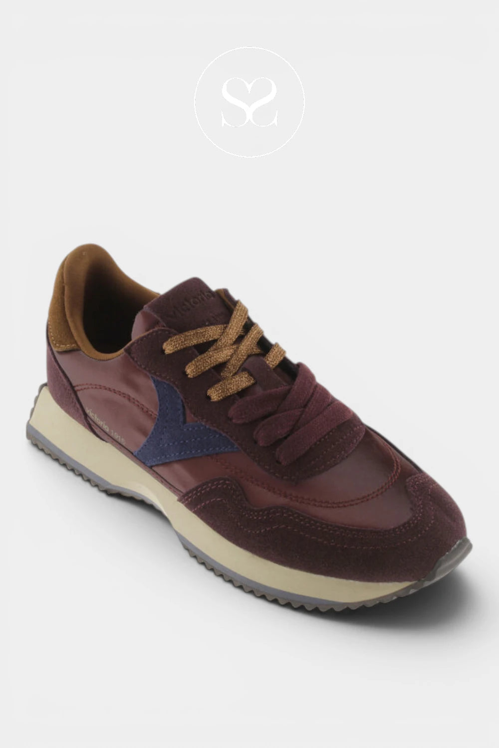A low-top sneaker in burgundy and brown suede and mesh, featuring a navy blue side stripe, brown laces, and a beige midsole, shown on a light gray background.