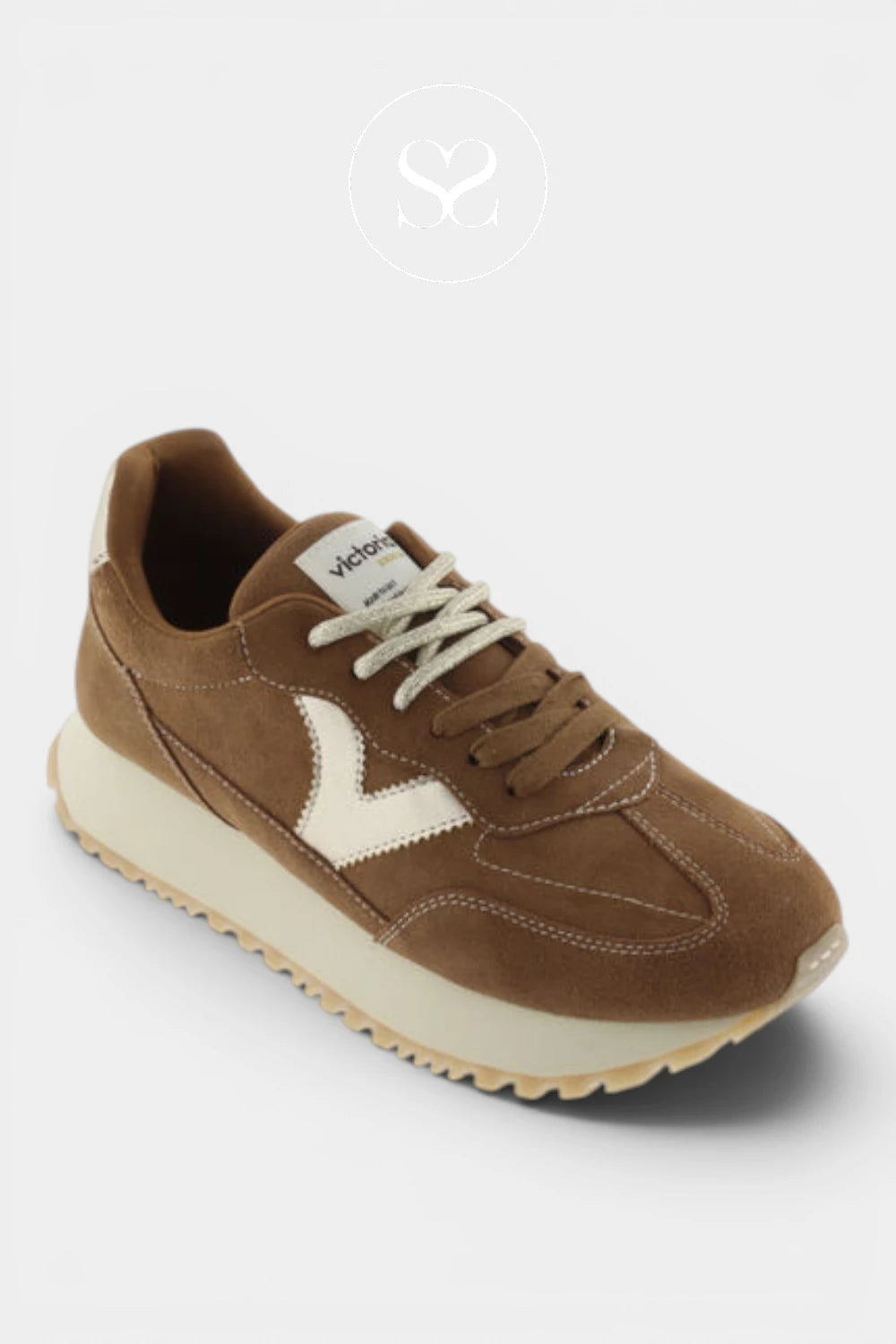A brown suede sneaker with cream-colored side stripes, laces, and sole, shown from a three-quarters angle on a light gray background.