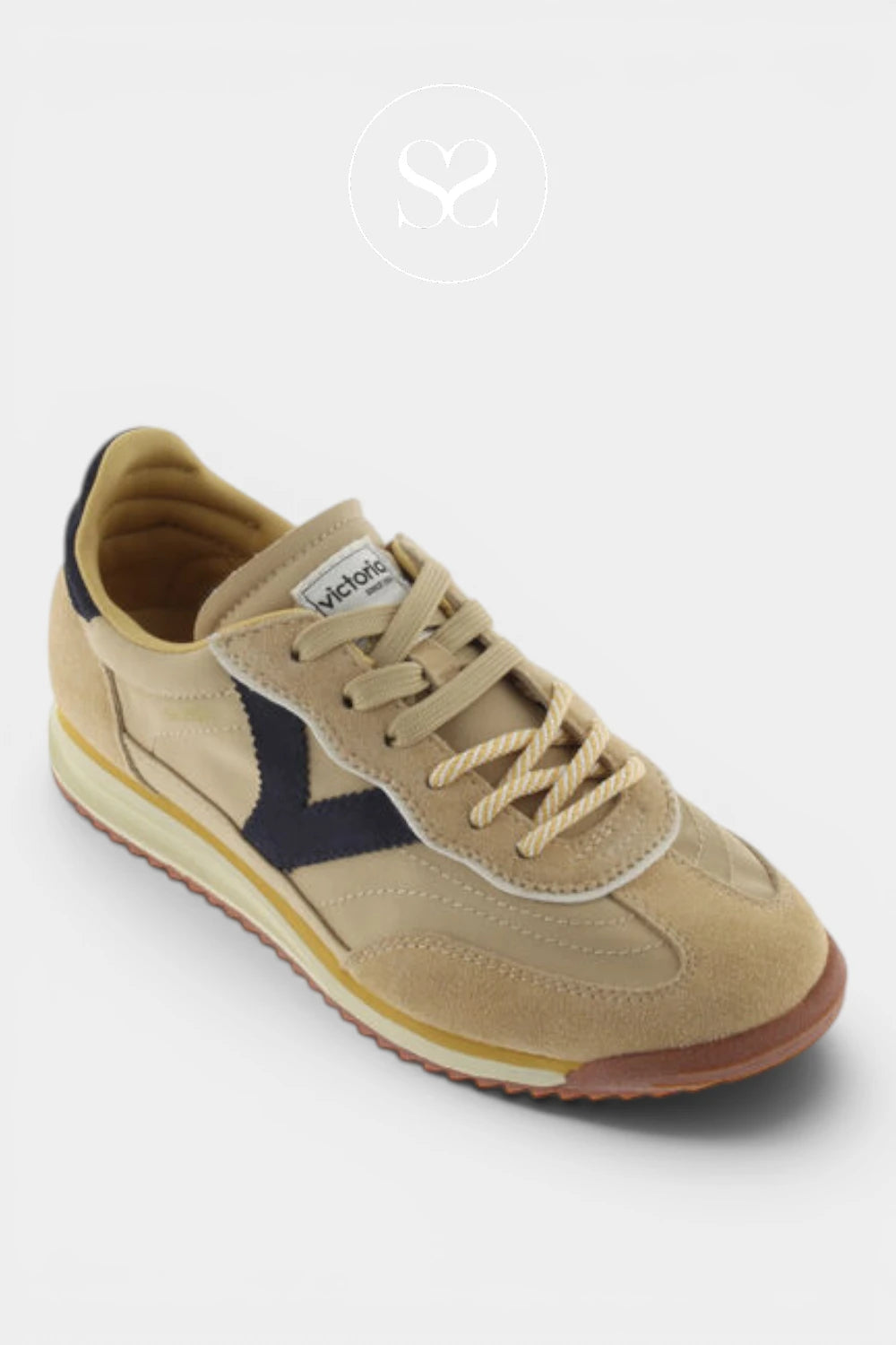 A single vintage-style sneaker by Webkinz in beige suede and canvas, featuring a navy blue chevron logo, beige laces, and a brown gum sole, set against a light gray background with a faint brand watermark.