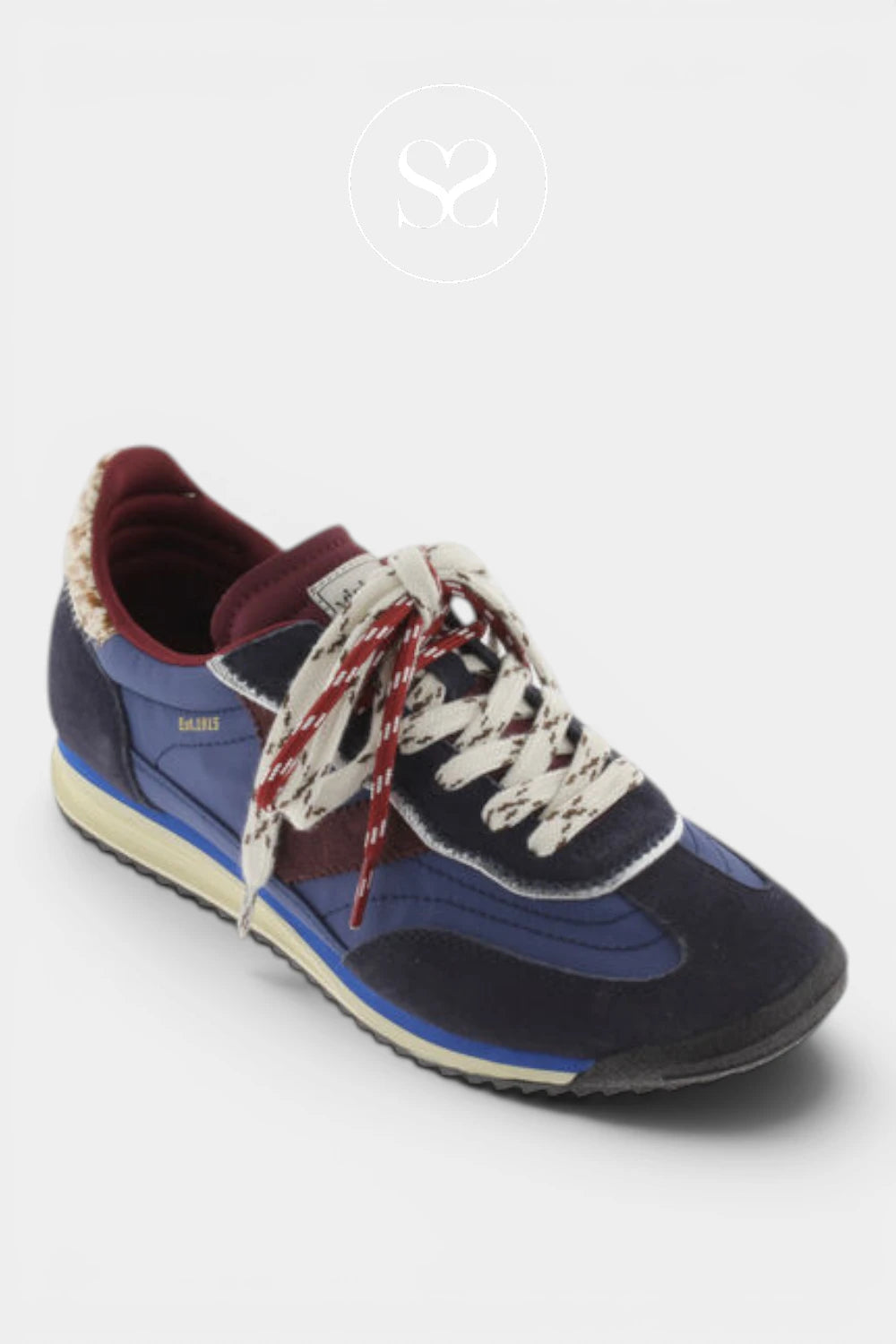 A low-top sneaker in navy blue suede and synthetic fabric, featuring cream-colored laces with red and white stripes, a burgundy inner lining, and a cream midsole, shown on a light gray background.