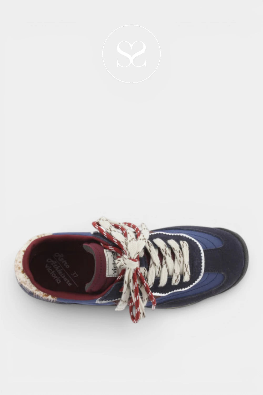 A single low-top sneaker shown from a top-down view on a light gray background. The shoe features a navy blue suede upper with blue mesh panels, a burgundy inner lining, and chunky white laces with red and white braided details.