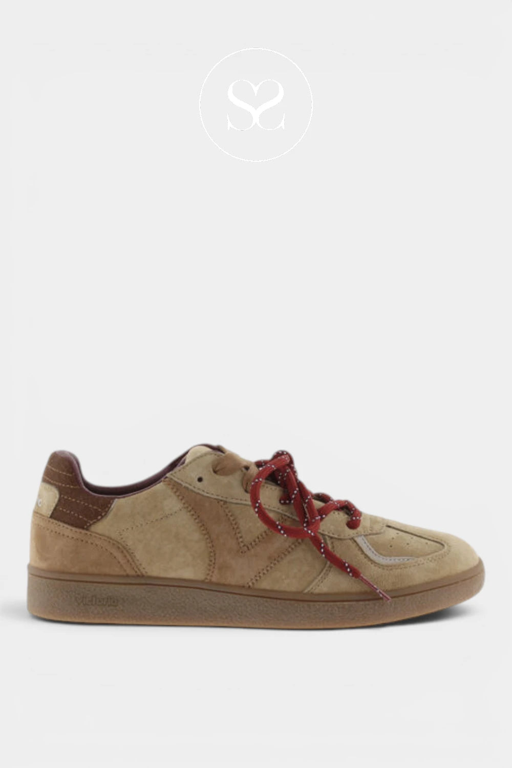 A low-top suede sneaker in tan and brown with red patterned laces, shown in profile against a light gray background.