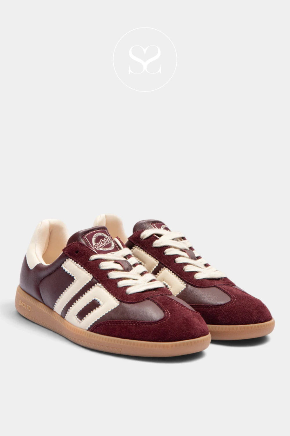 A pair of low-top sneakers in burgundy suede and leather with cream stripes, cream laces, and tan rubber soles, displayed on a light gray background.