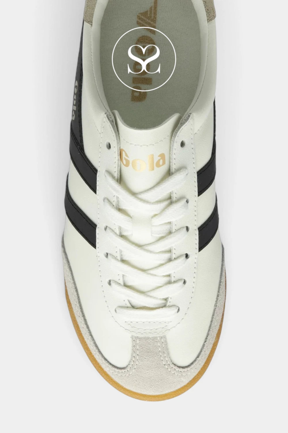 A top-down view of a retro-style low-top sneaker in off-white leather with black side stripes, a tan suede toe cap, and a gum sole. The brand name 'Sola' is printed in gold on the tongue, and a circular logo is visible on the insole.