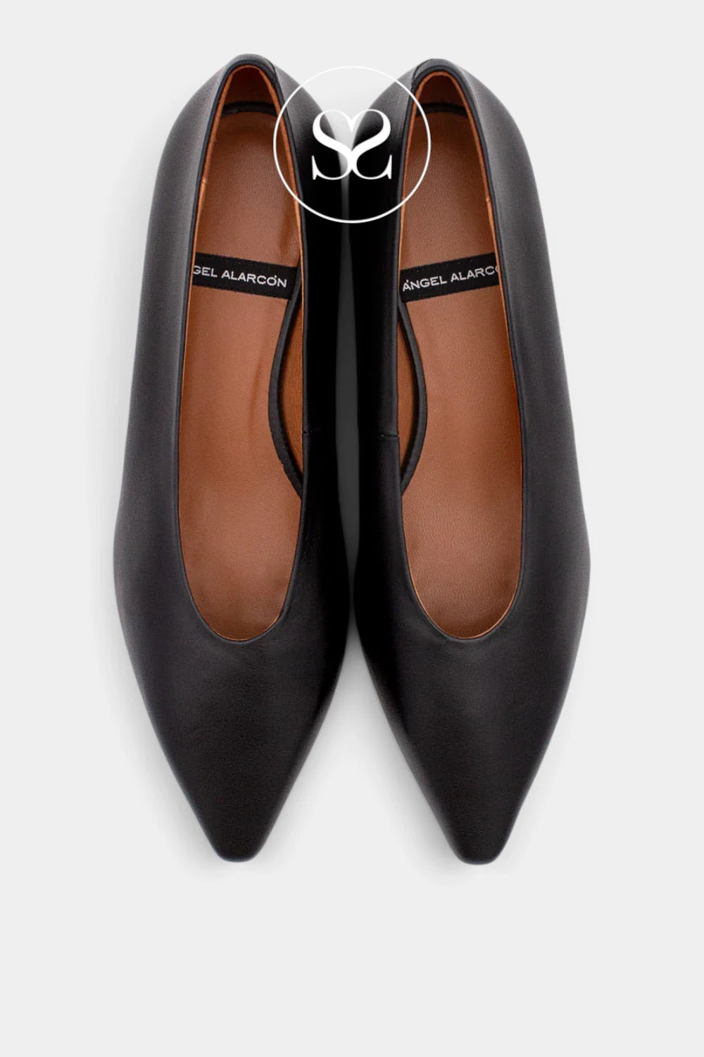 A pair of black leather pointed-toe pumps with a warm brown insole, shown from a top-down view on a light gray background. 