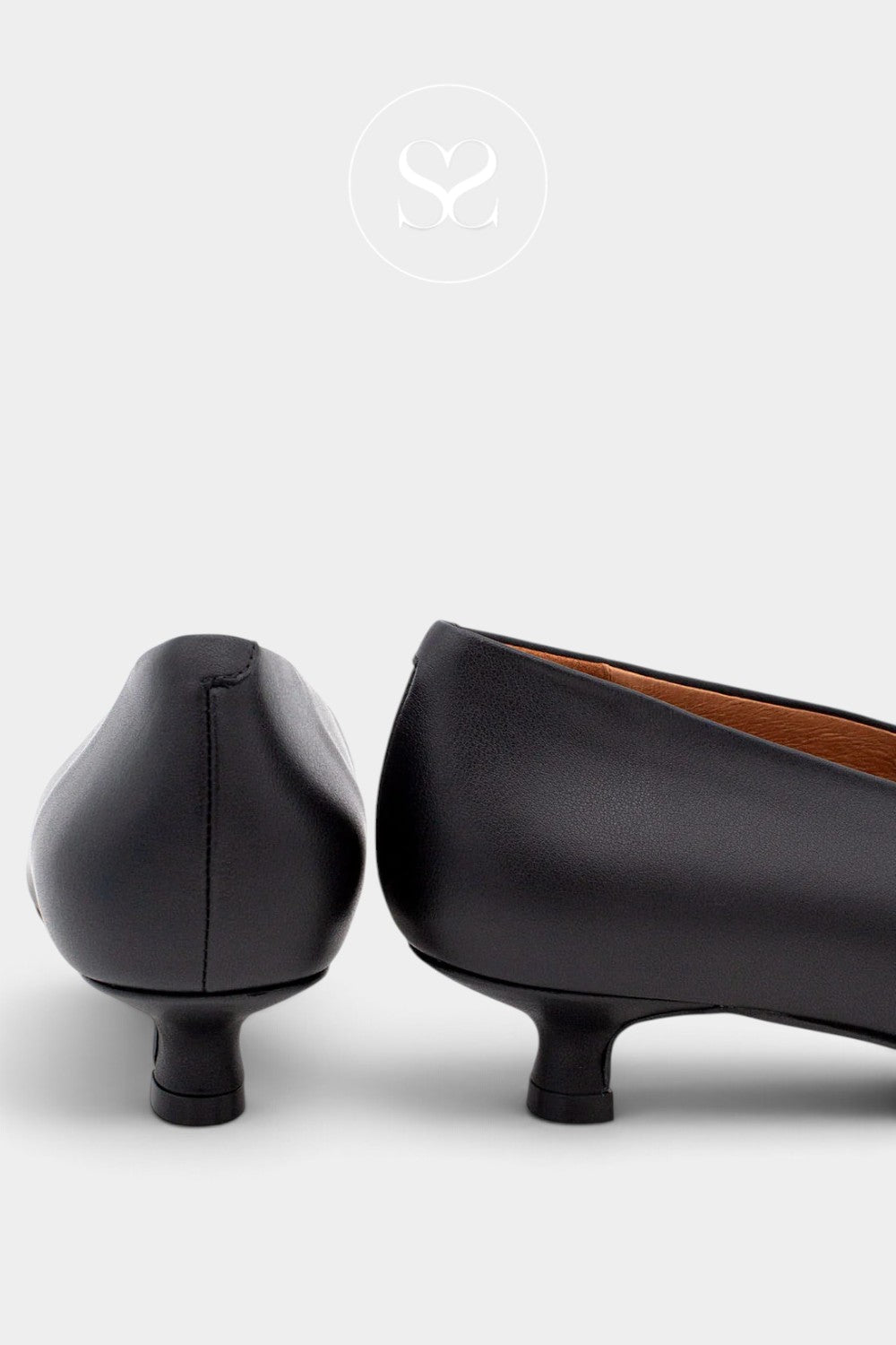 A pair of black leather low kitten heels shown from the side and back angles against a light gray background.