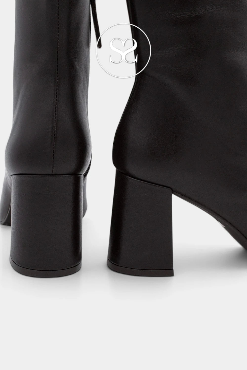 Close-up of black leather ankle boots with chunky block heels, showing the back and side details against a light gray background.