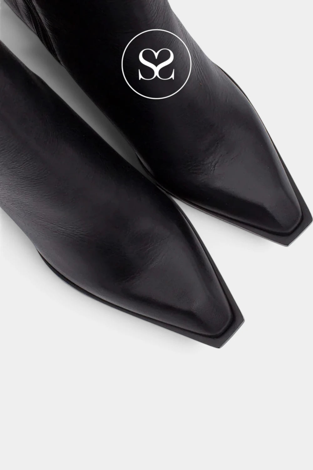 Close-up of a pair of black leather pointed-toe boots on a light gray background, with a white circular logo featuring interlocking 'S' initials printed on one boot.