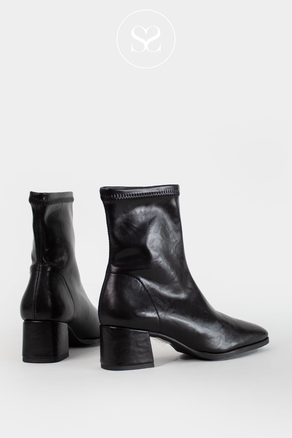 A pair of Miss Elastic black leather sock boots with block heels, shown from the side and back on a light gray background. A circular logo with an 'Sheneil Shooes logo' is visible at the top center.