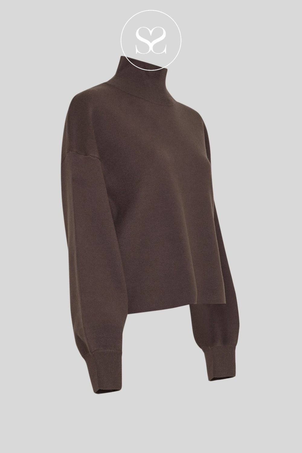 A cosy dark brown knit turtleneck sweater with a relaxed, oversized fit and ribbed cuffs, shown on a neutral light gray background with a brand logo overlay at the top.