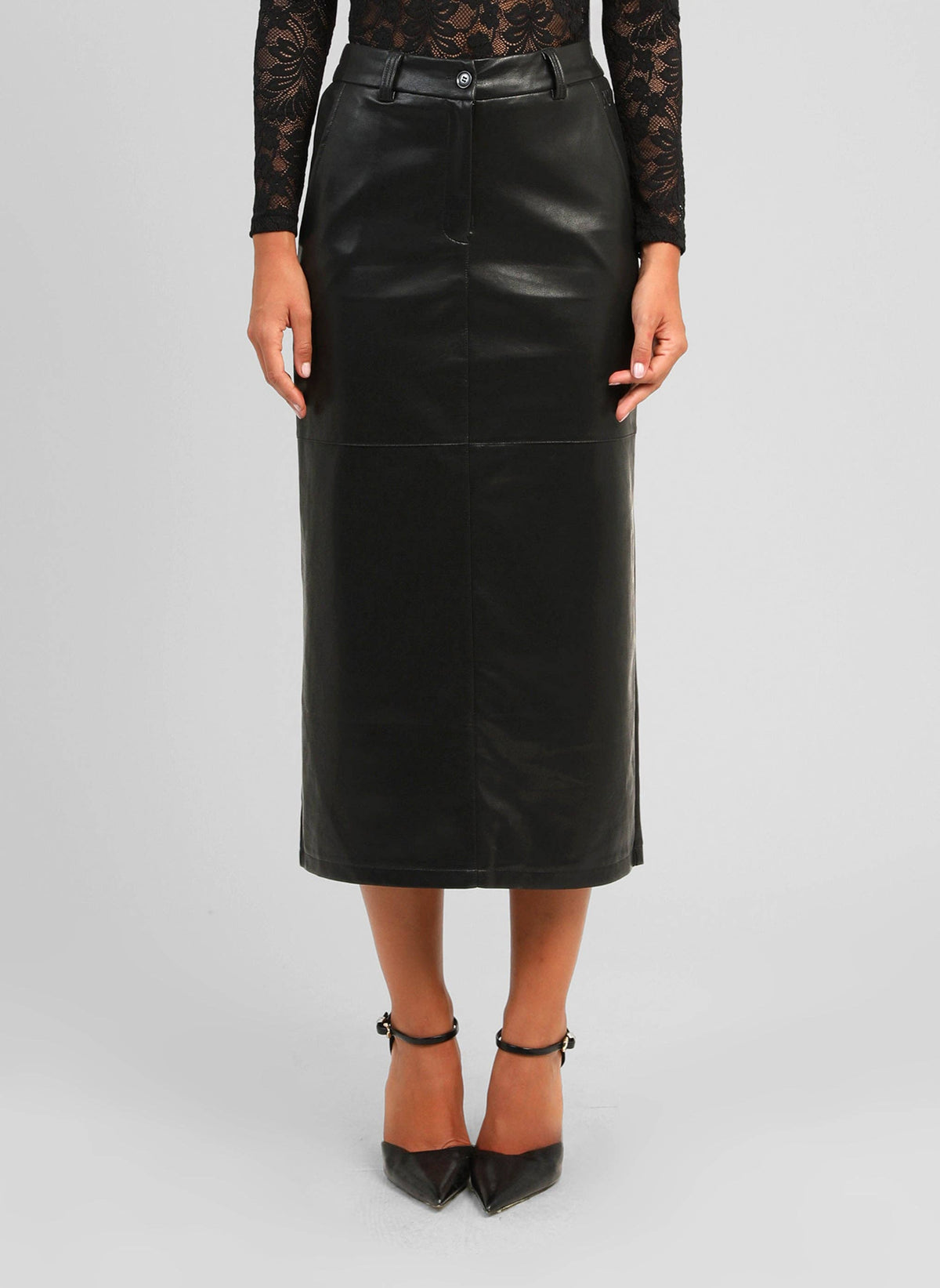 A model wearing a black faux-leather midi skirt with a front zipper, paired with a black lace long-sleeve top and black pointed-toe heels, against a light gray studio background.