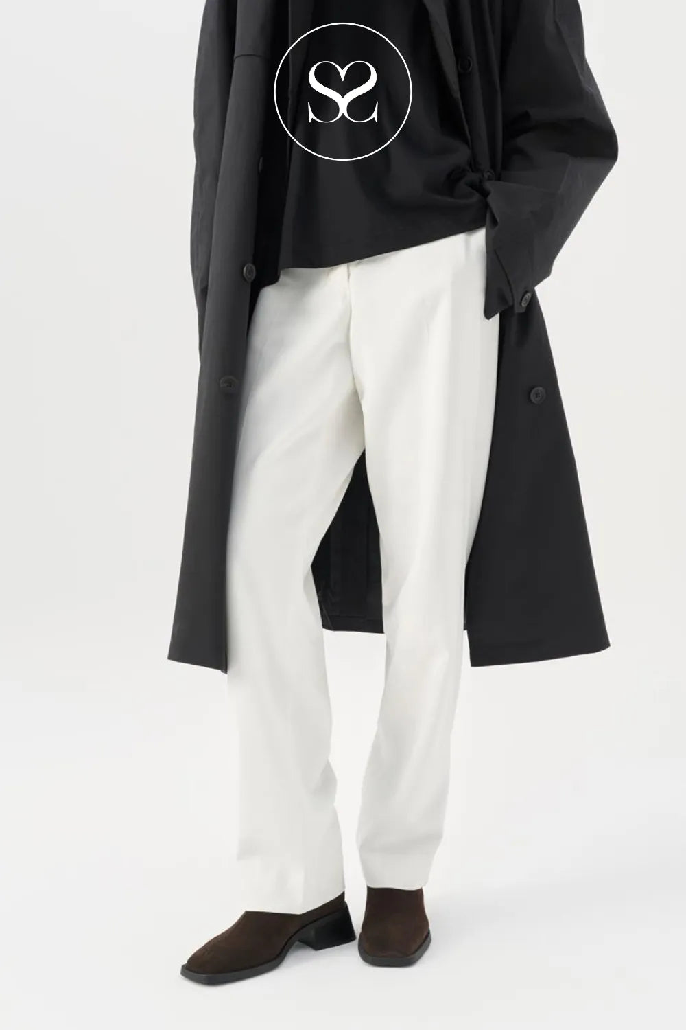 Woman wearing brown suede Vagabond Blanca ankle boots with white trousers and brown coat