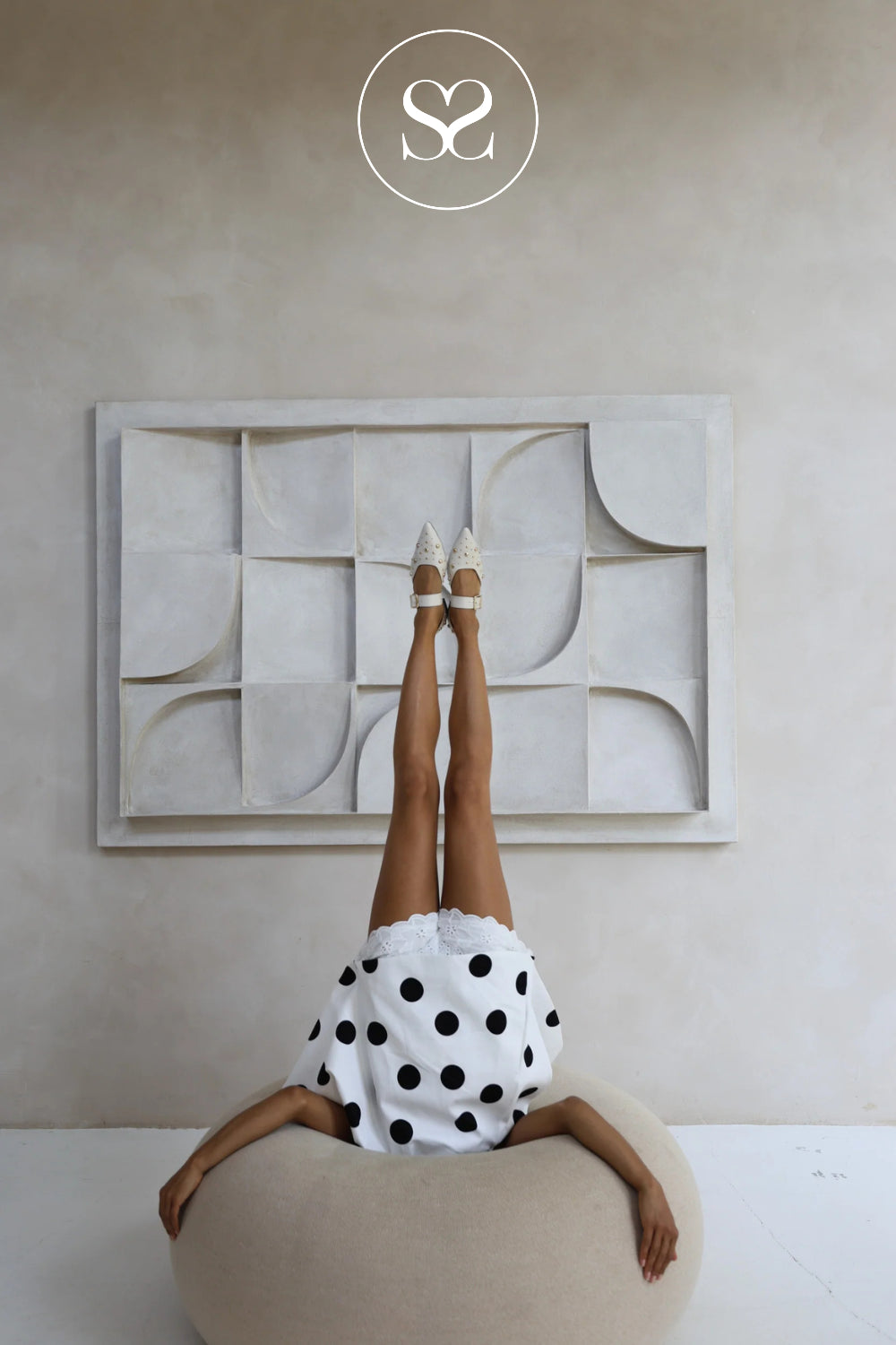 Person in a polka dot dress standing on a stool withoff white flat shoes from babouche