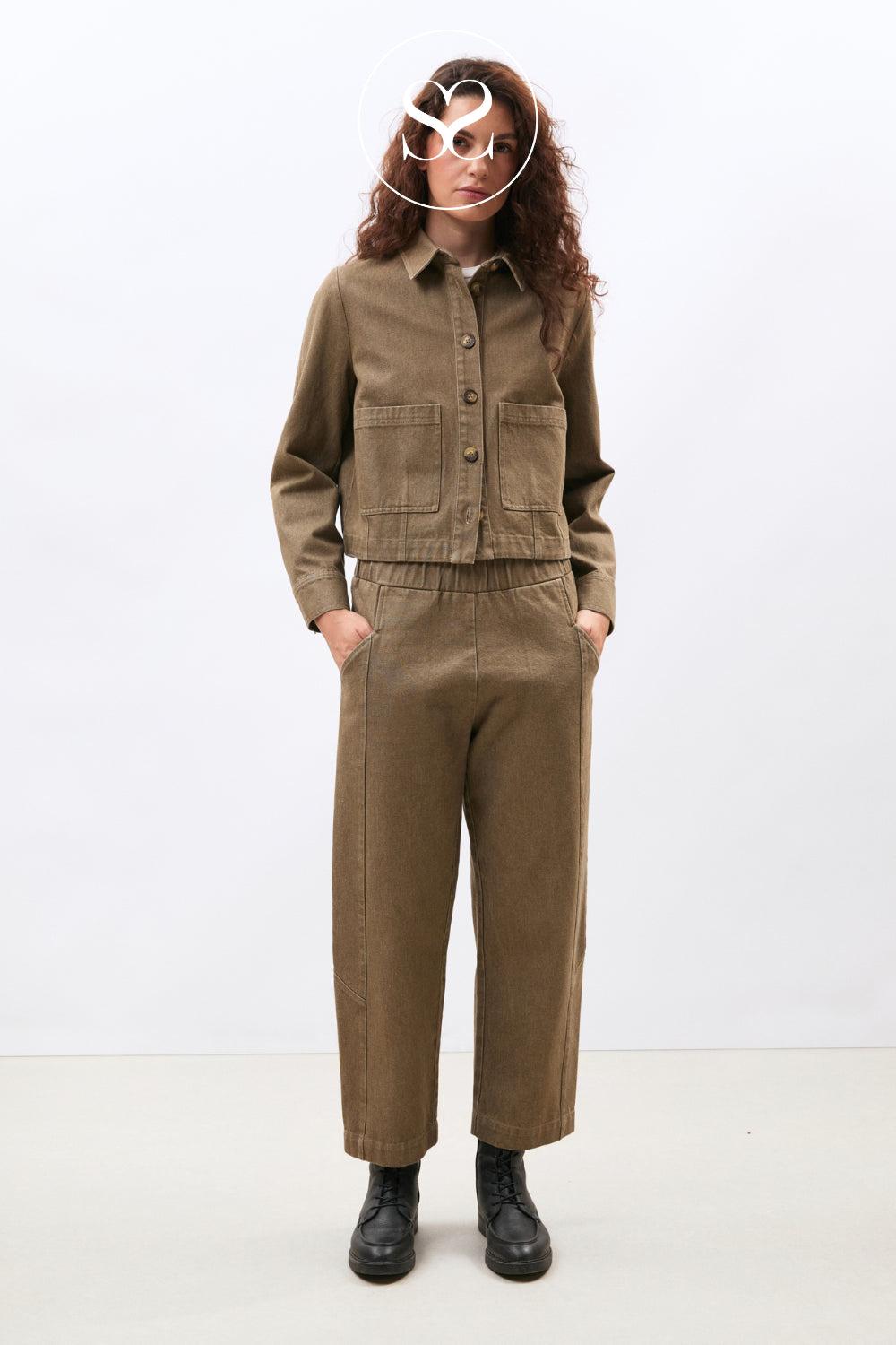 A model wearing a matching brown corduroy button-up shirt and trousers set, styled with black leather boots against a plain white studio background.