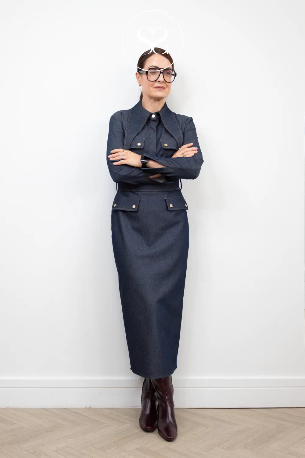A woman wearing a dark navy blue tailored dress wearing wonders burgundy knee high dress boots