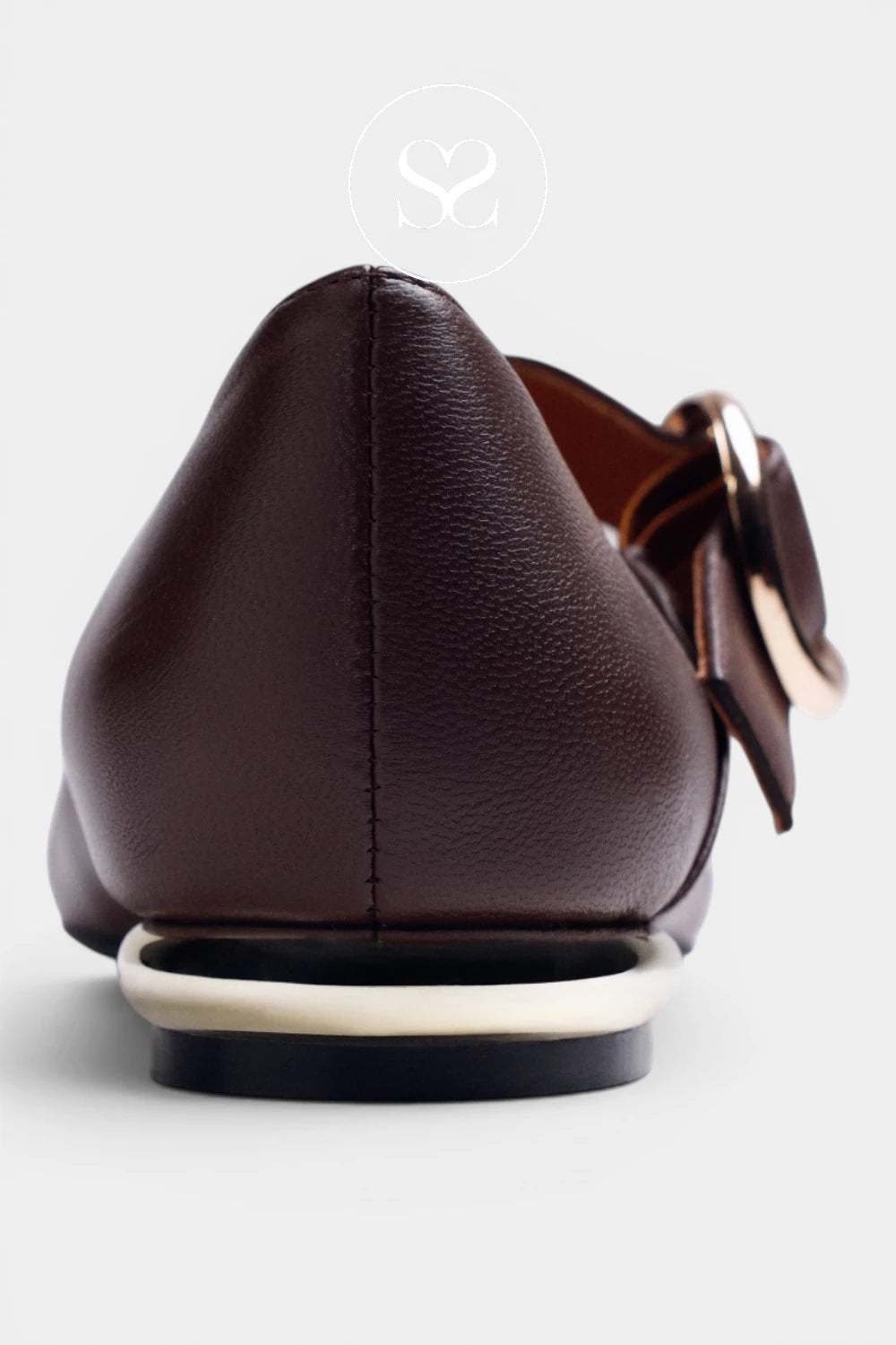 A close-up rear view of a dark brown leather pointed-toe flat shoe with a decorative brown bow and gold-tone metal accents on the side, set against a light gray background.