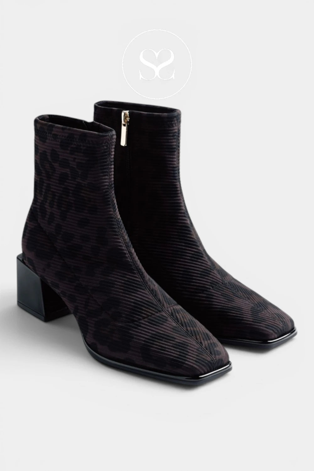 A pair of black ankle boots with a subtle textured pattern, featuring a low block heel and a side zipper, shown against a light gray background.