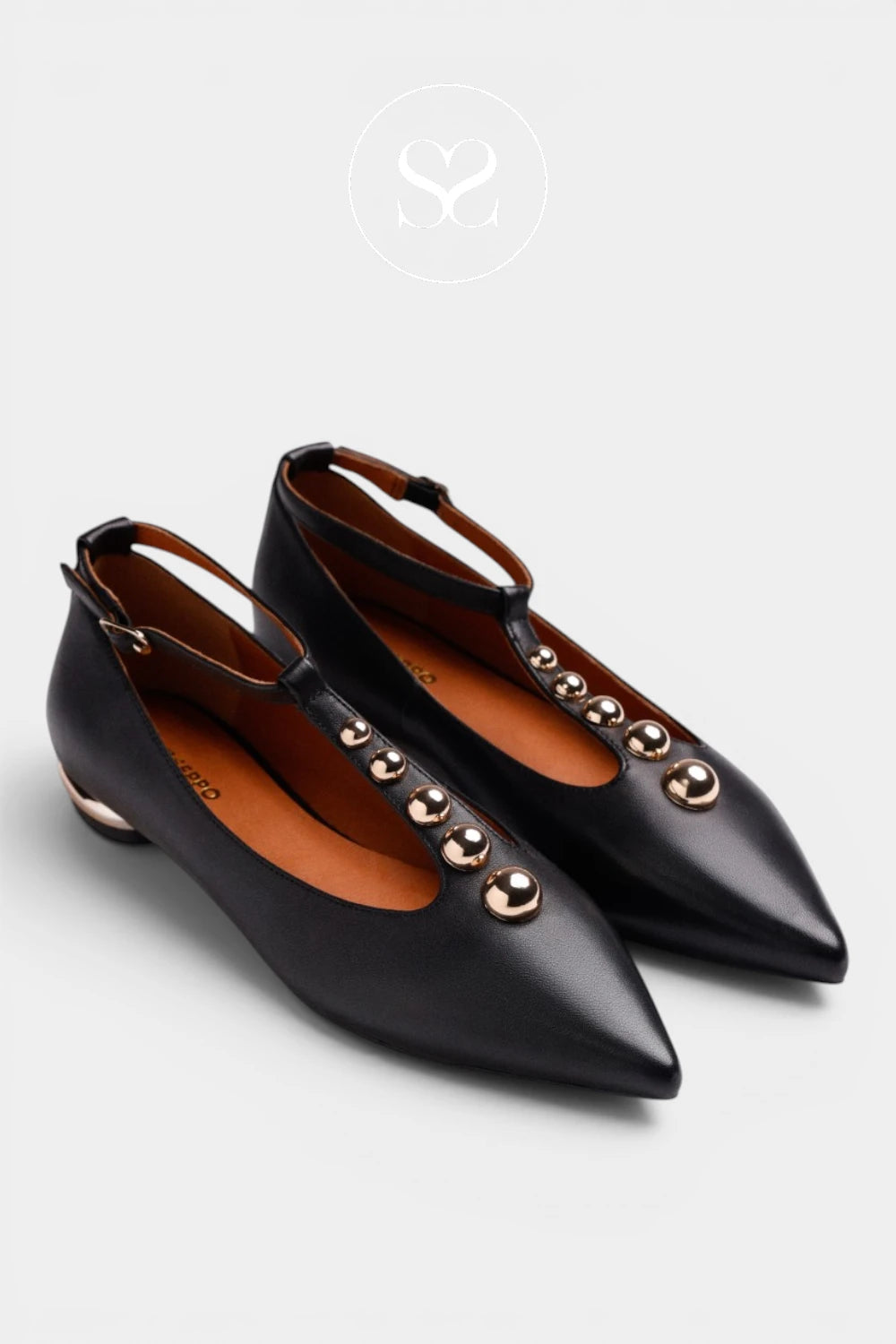 A pair of black leather pointed-toe flats with a low block heel and decorative gold-tone metal studs down the front strap, shown on a light gray background.