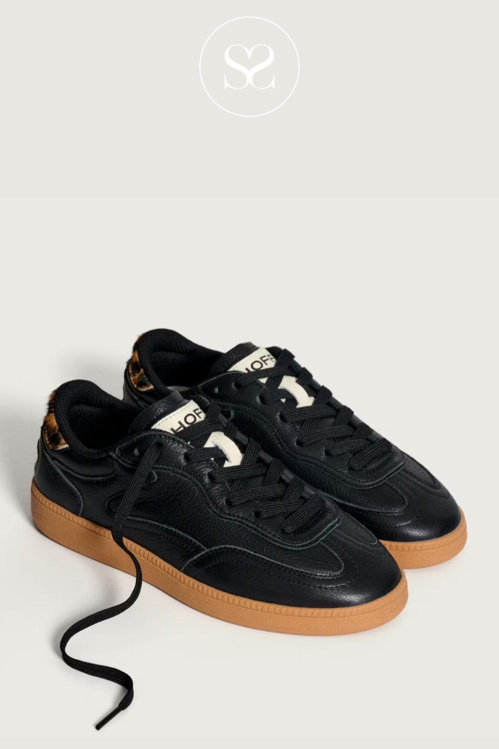 Black sneakers with brown gum soles on a light grey background. From Hoff