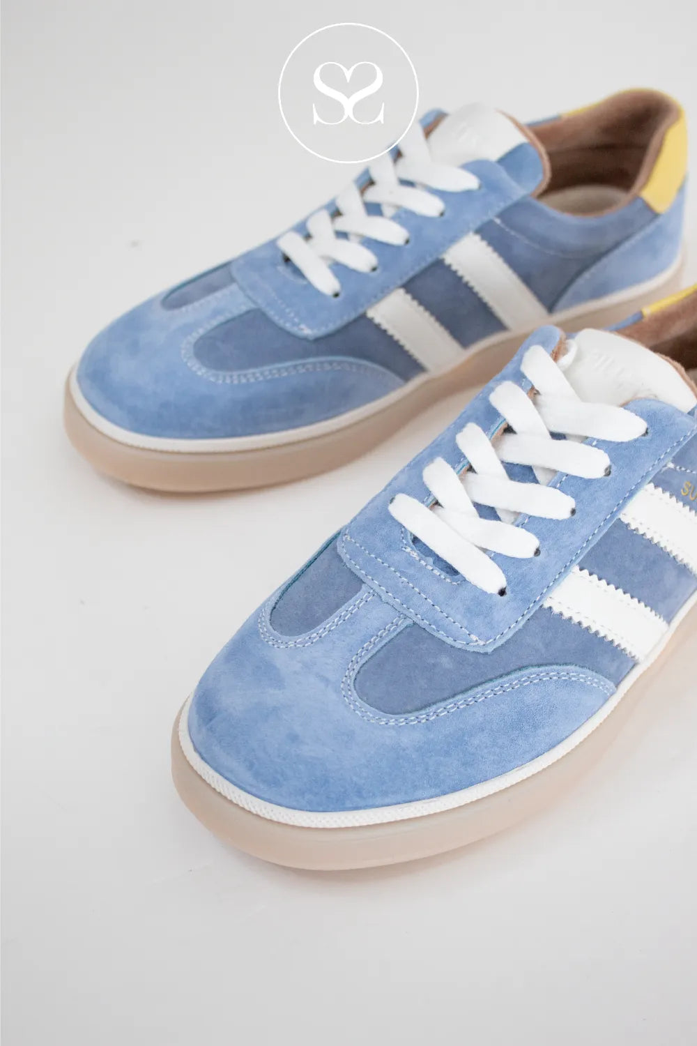 Blue sneakers with white laces and stripes. Fashion trainer with yellow heel cap.