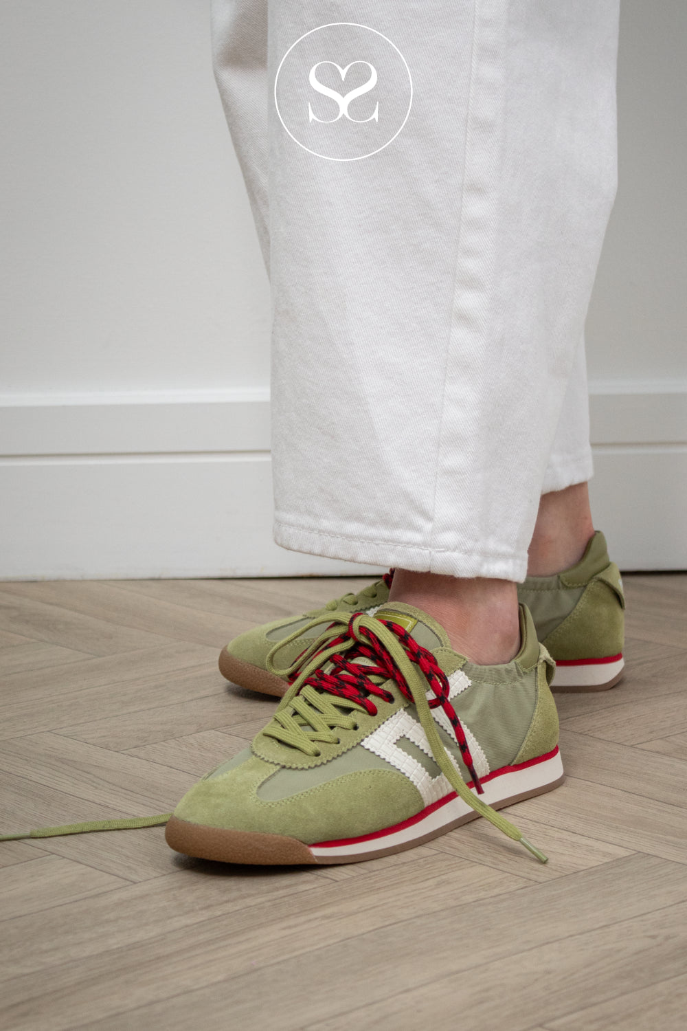 Green sneakers with red accents from Back 70 worn by a person on a wooden floor. Available in Sheneil shoes Galway Ireland