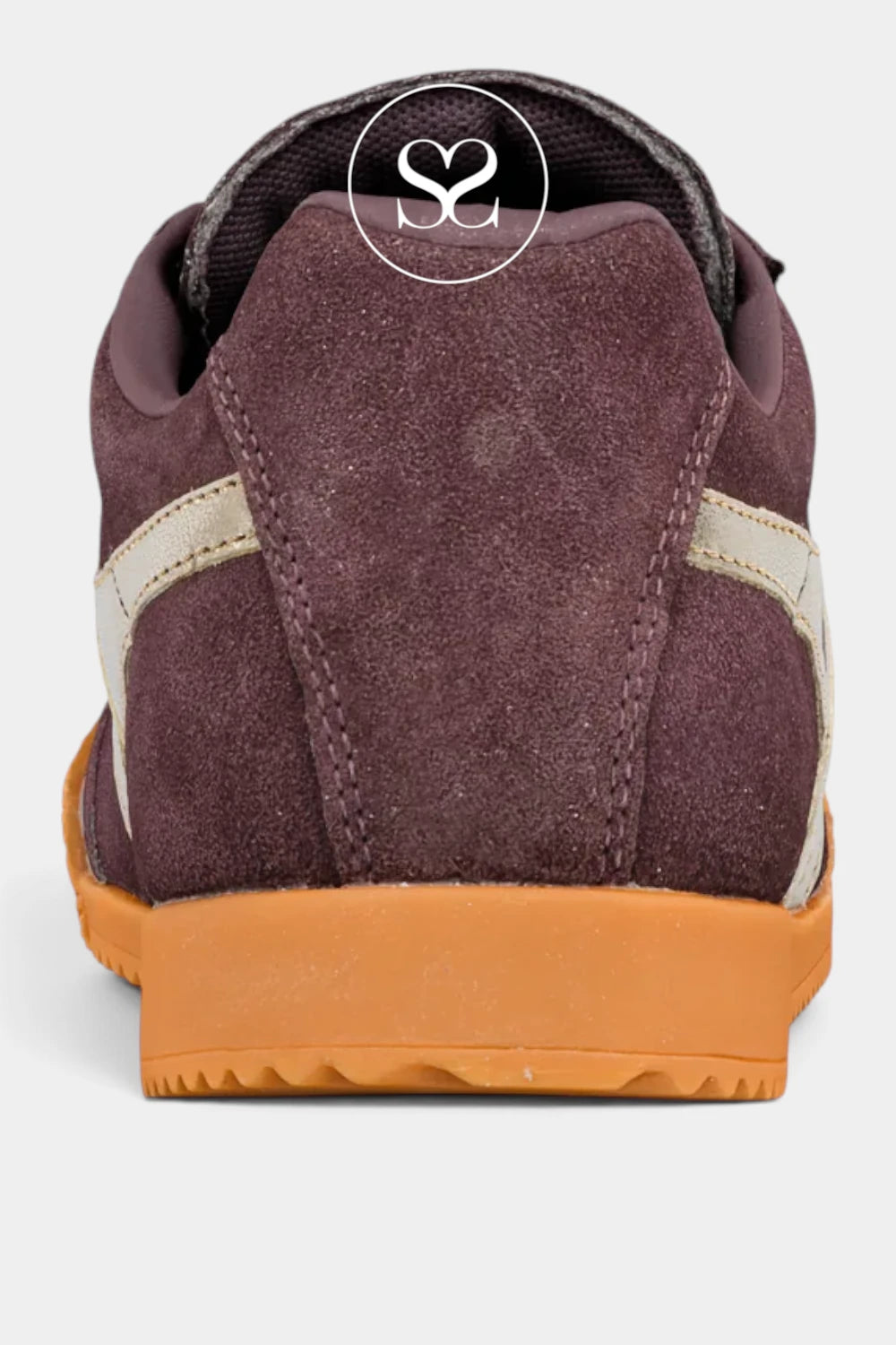 A close-up rear view of a low-top sneaker in dark plum-brown suede with cream side stripes and a gum orange sole, shown on a light gray background.