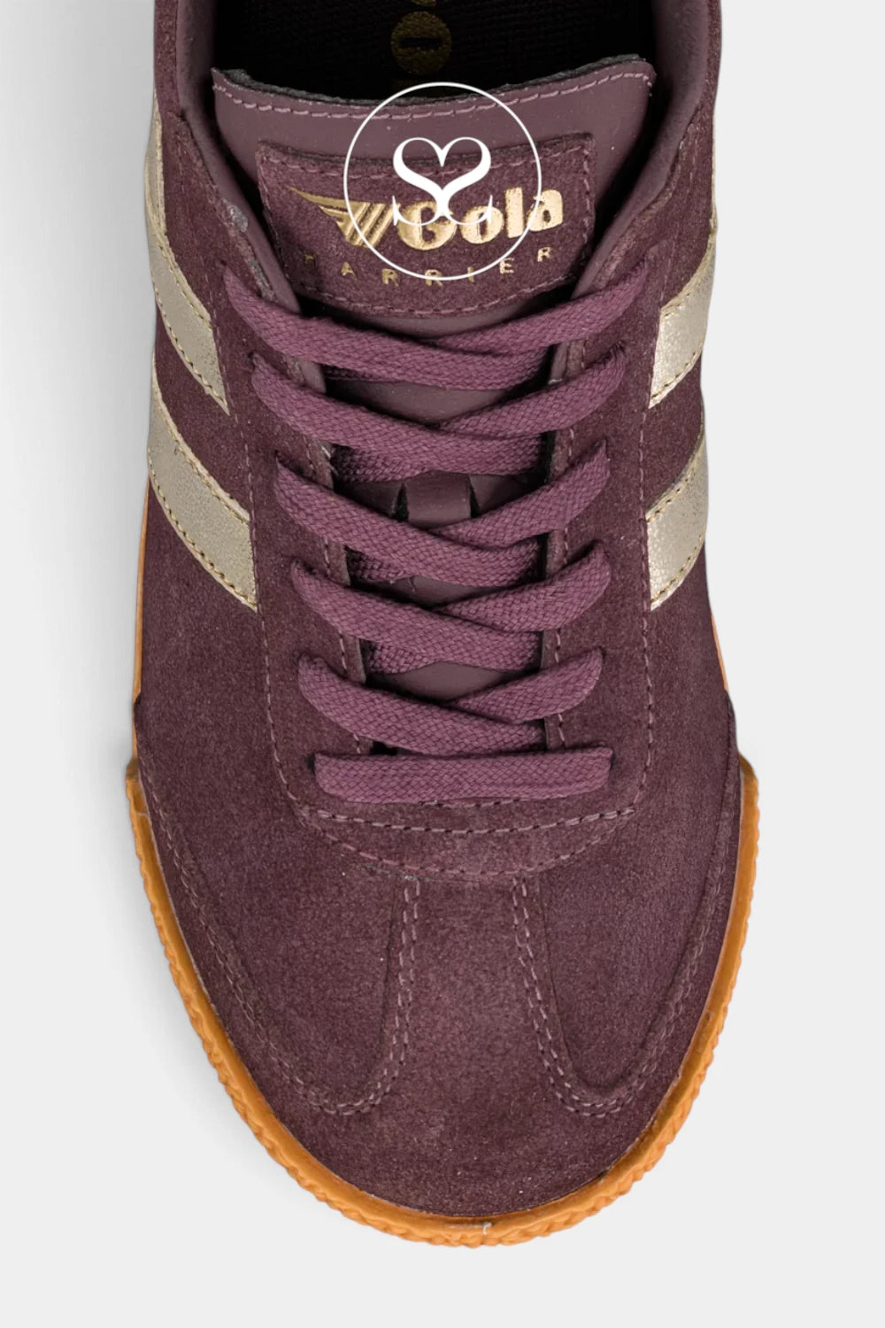 A close-up top-down view of a suede sneaker in a deep plum purple color, featuring beige side stripes, purple laces, and a brown gum sole. 