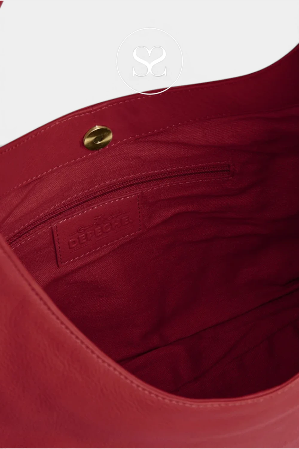 Close-up of the interior of a red leather bag, showing a zippered pocket with a debossed logo patch and a gold-tone snap closure. The brand name 'Celine' is visible on the patch.