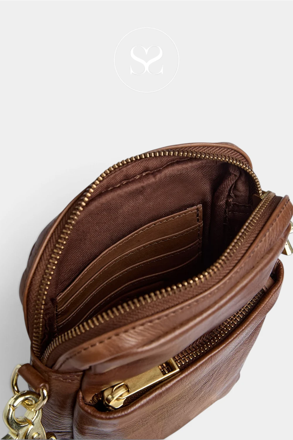 Close-up of a brown leather crossbody bag showing the interior with multiple card slots, gold-tone zippers, and a matching brown fabric lining, photographed on a light gray background.