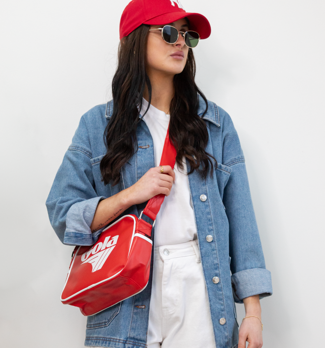 Woman wearing red gola crossbody bag with sunglasses and denim shirt - in Ireland