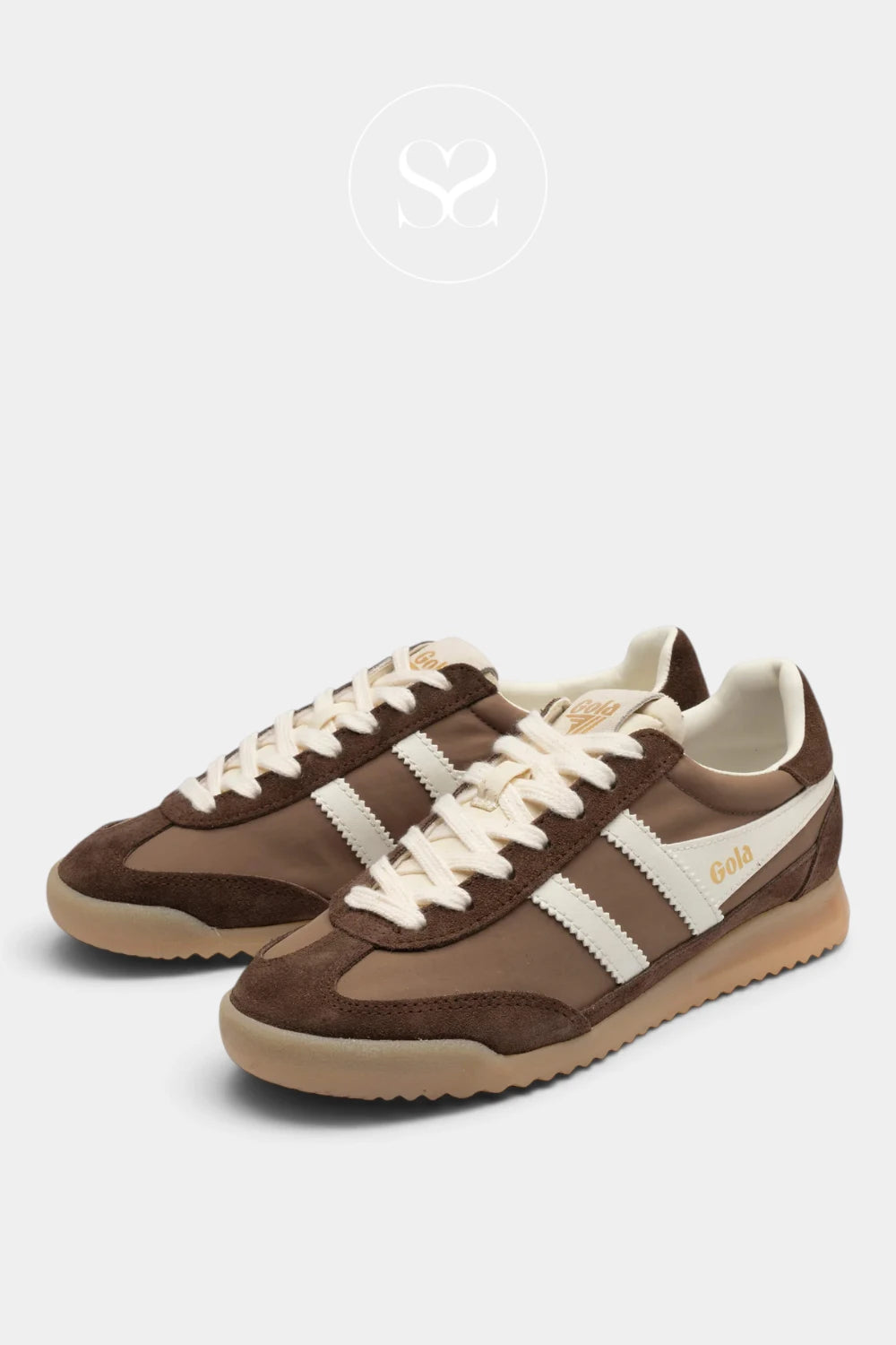 A pair of retro-style brown sneakers with cream stripes, cream laces, and a gum sole, displayed on a light gray background with a faint brand logo at the top.