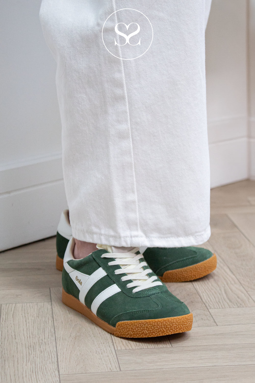 Woman wearing green and white trainers with gum sole from Gola