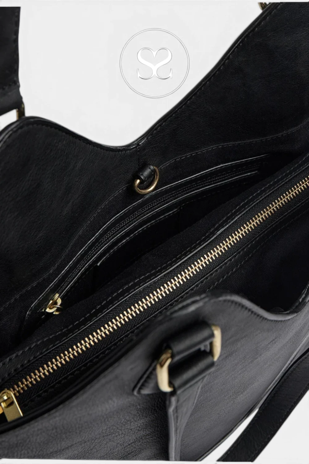 Close-up of a black leather handbag interior showing a zippered compartment with gold-tone hardware and a white background.