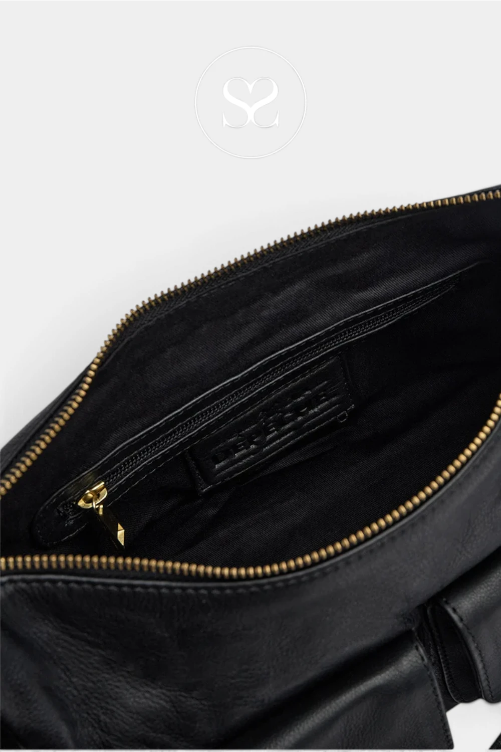 Close-up of the interior of a black leather bag, showing a black fabric pocket with a gold zipper and a black leather brand label that reads 'SARABACI'.
