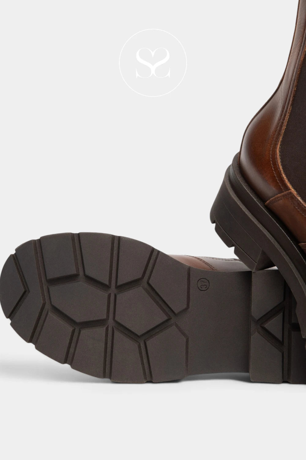 Close-up of a brown leather boot showing the textured dark brown rubber sole and part of the brown leather upper against a light gray background.