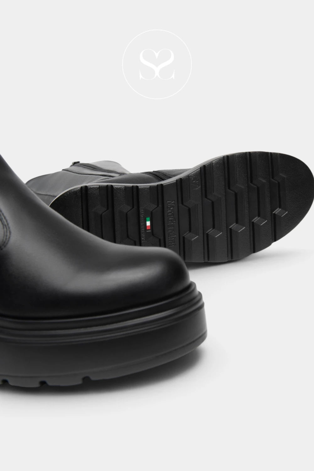 Close-up of a black leather boot with a chunky sole, showing the side profile and the treaded outsole with a small Italian flag detail.