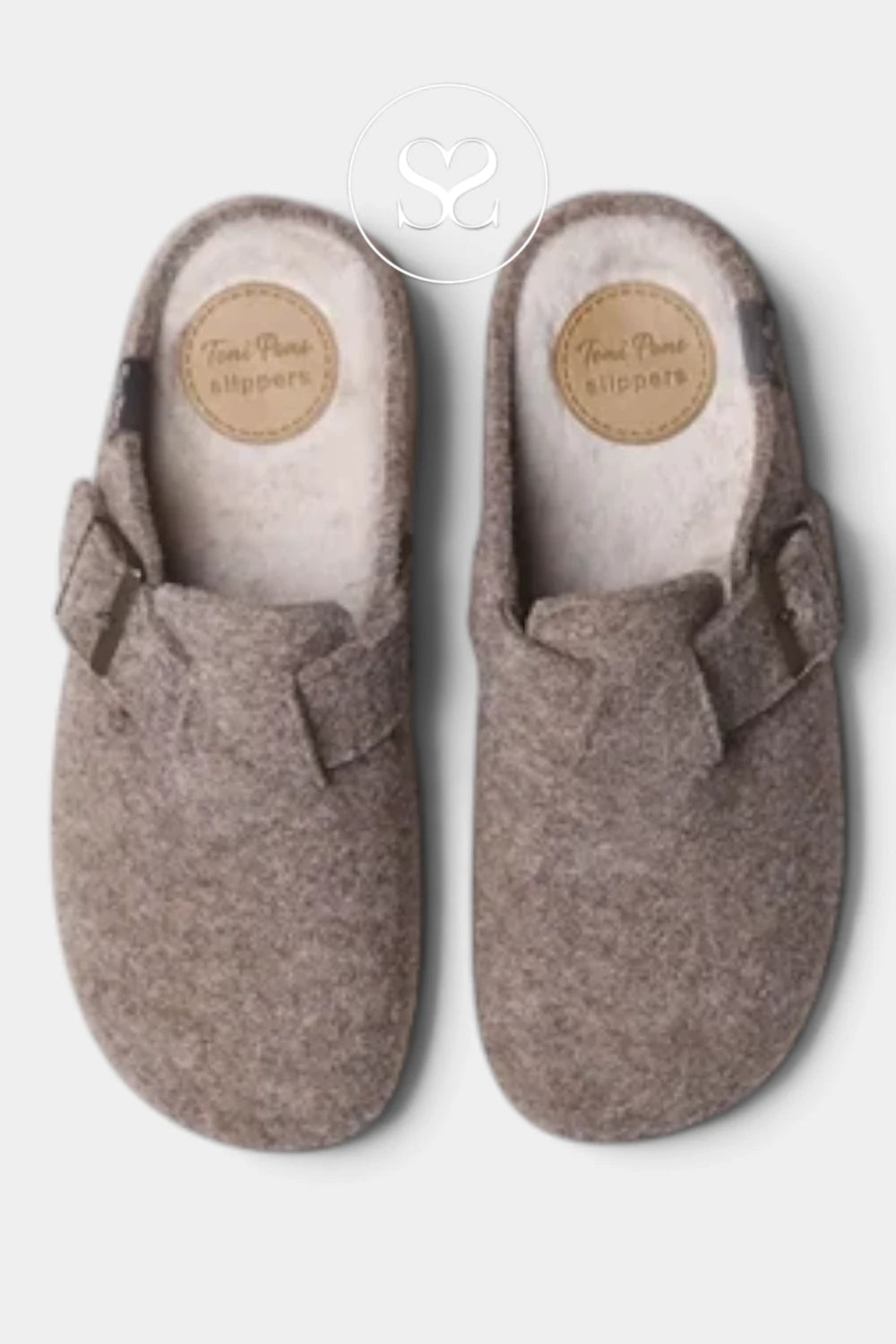 A pair of felt slip-on clogs in a warm taupe-brown color, shown from a top-down view on a light gray background. Each slip-on shoe features a decorative fabric bow on the outer side and a circular tan brand patch on the insole that reads 'Toni Pare slippers'.