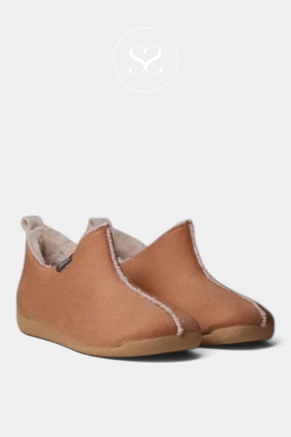A pair of slip-on toddler slipper shoes in tan faux leather with a soft beige fleece lining, shown against a light gray background with a faint brand logo at the top.