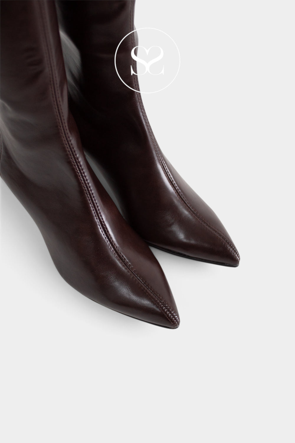 A close-up of a pair of dark brown leather pointed-toe sock boots from Miss Elastic, featuring a circular 'Sheneil Shoes' logo watermark near the top.