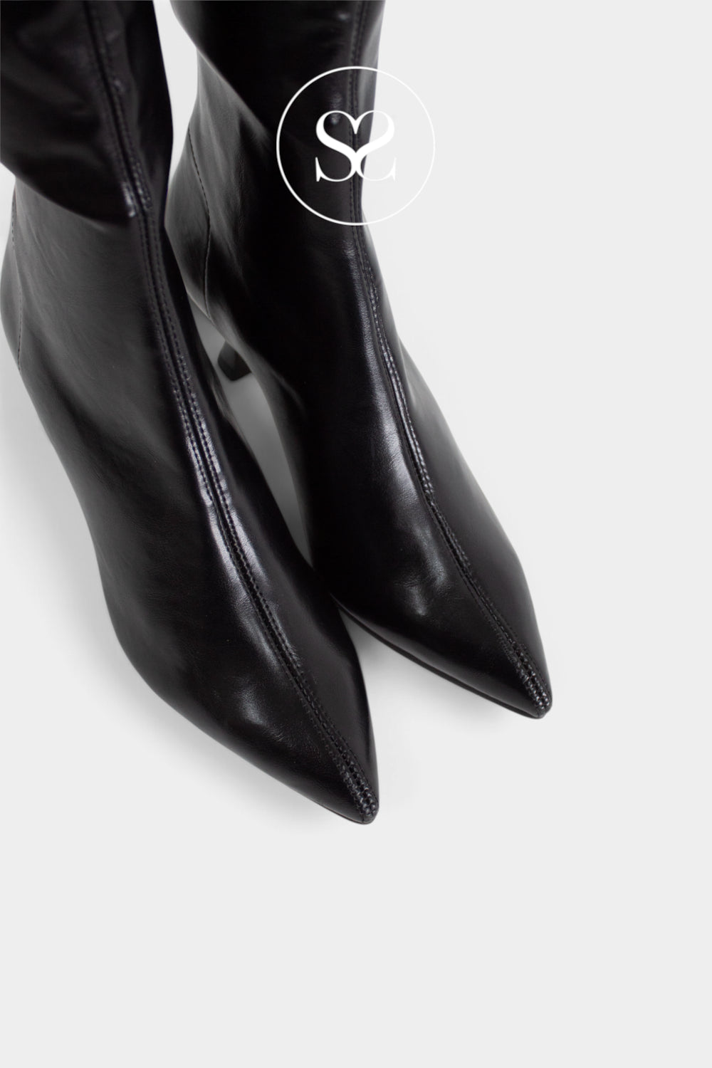 Black pointed-toe sock boots with a glossy finish, shown from a high-angle close-up on a light grey background with a circular 'Sheneil' logo watermark.