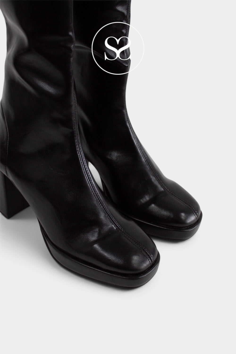 Black leather knee-high boots with a block heel and square toe, shown on a light gray background with a white circular 'Sheneil Shoes' logo overlay near the top. Boots from Miss Elastic Brand