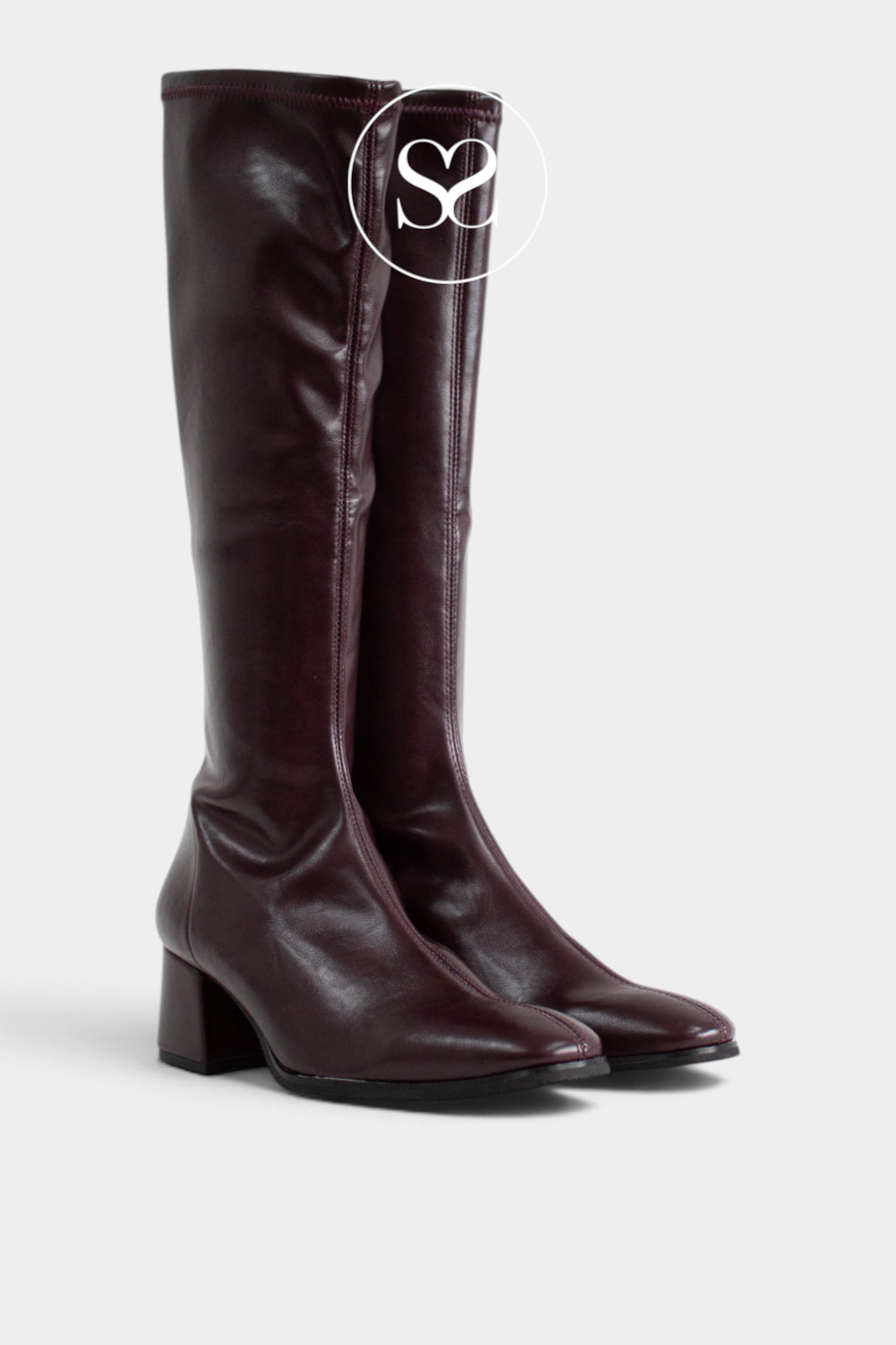 A pair of knee-high leather boots in a deep burgundy color, featuring a low block heel and rounded toes, shown against a light gray background with a white circular 'Sheneil Shoes' logo overlay near the top.
