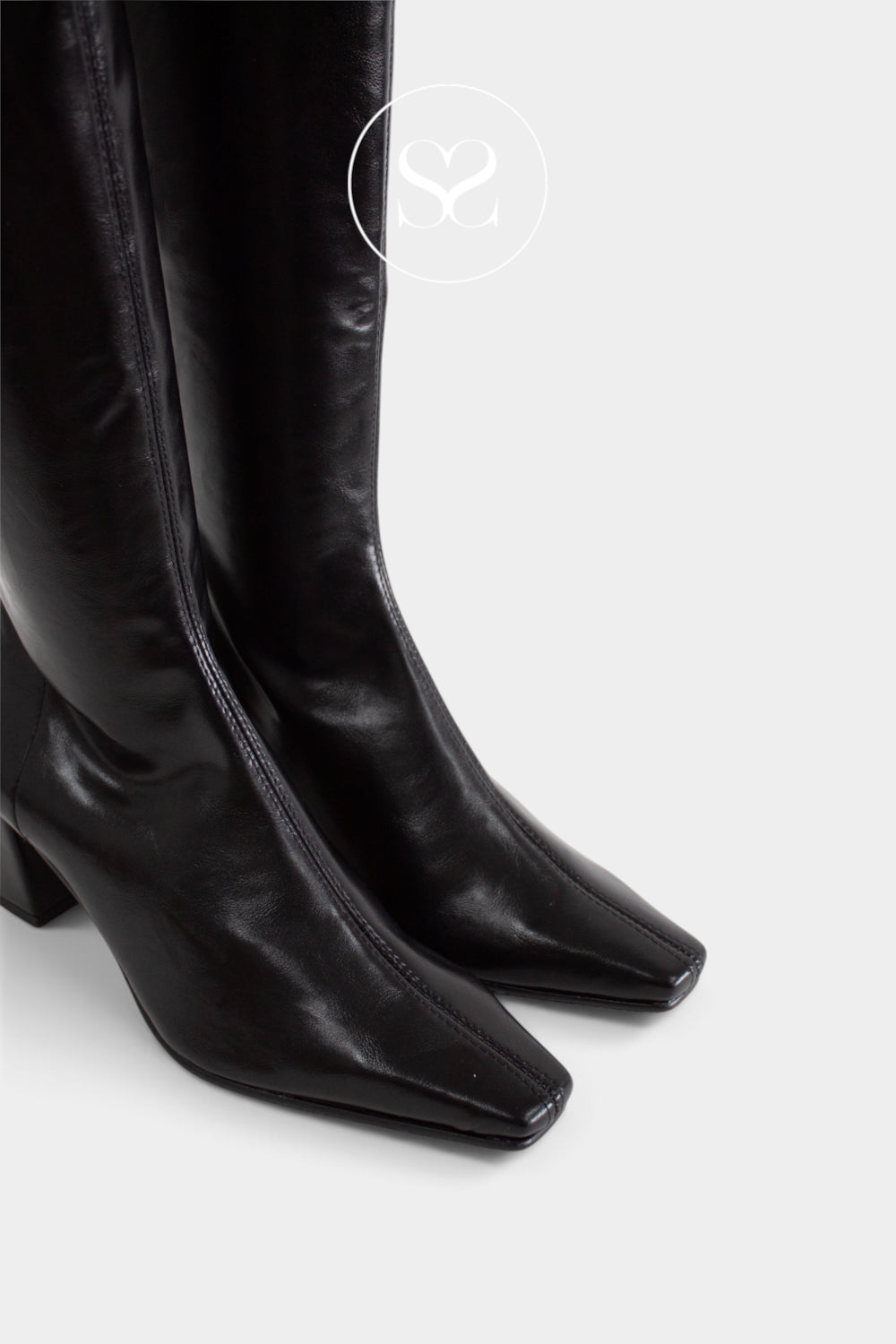 Black leather pointed-toe knee-high boots with a block heel, shown against a light gray background with a faint Sheneil Shoes circular logo watermark near the top.