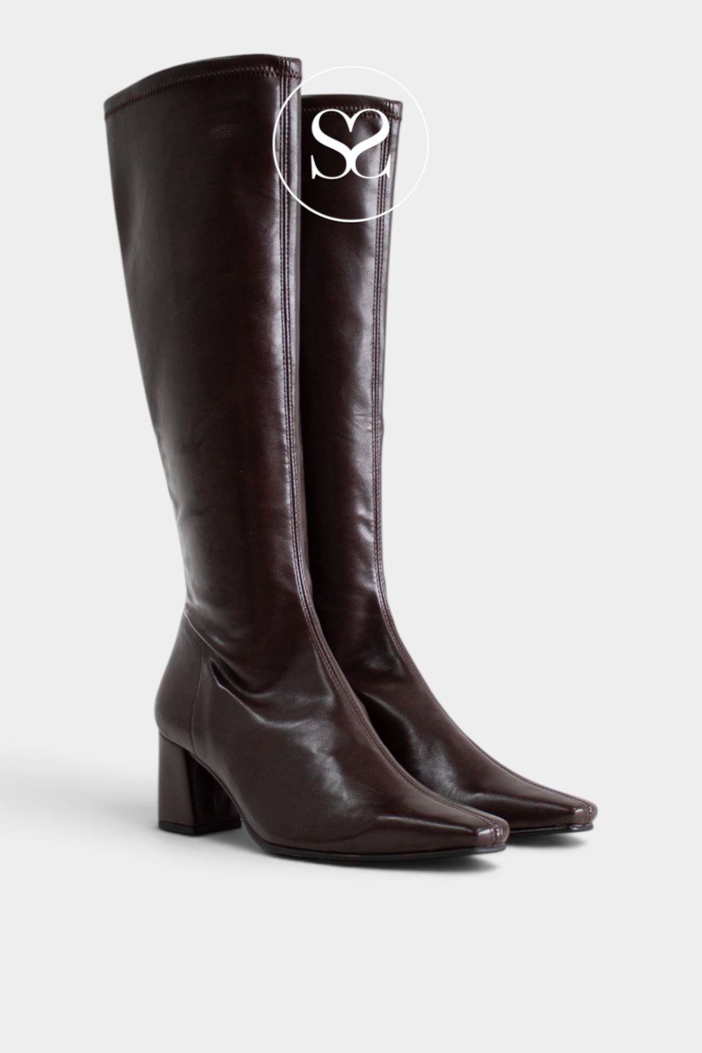 A pair of Miss Elastic dark brown leather knee-high boots with a block heel and pointed toe, shown on a light gray background with a white circular 'Sheneil Shoes' logo overlay near the top.