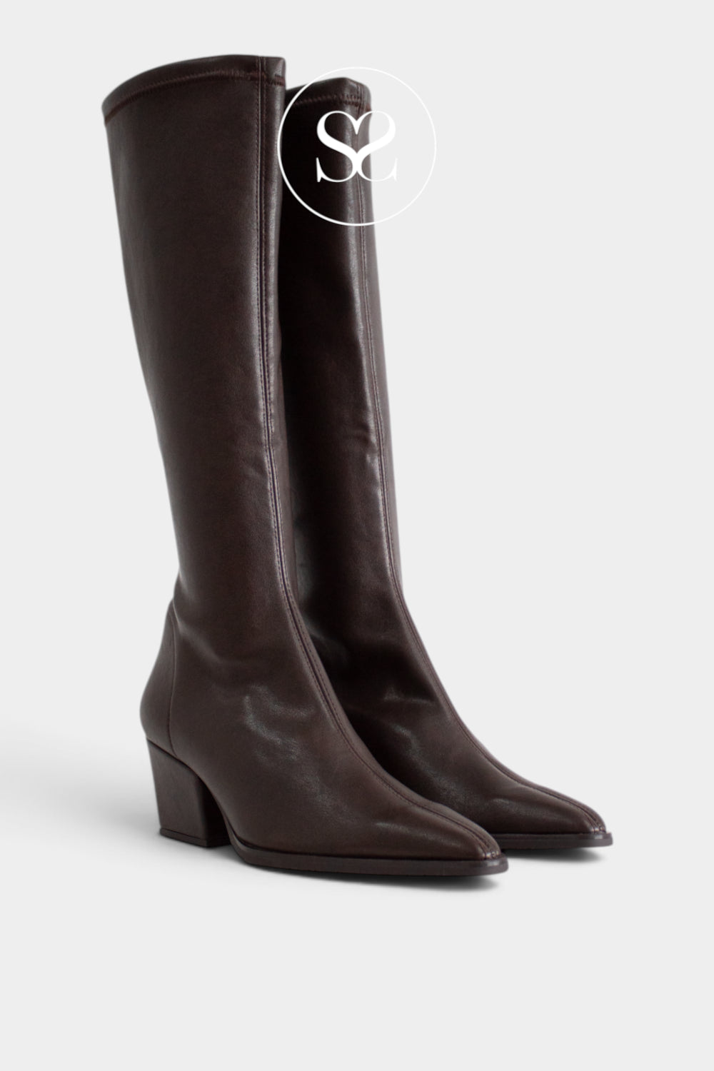 A pair of dark brown leather knee-high boots from Miss Elastic with pointed toes and low block heels, shown on a light gray background with a white circular 'SS' logo overlay near the top.