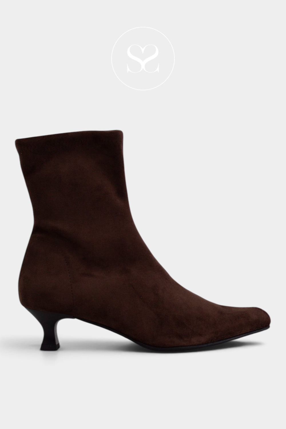 A dark brown suede ankle boot with a low kitten heel and a pointed toe, shown from a side profile on a light gray background from Miss Elastic