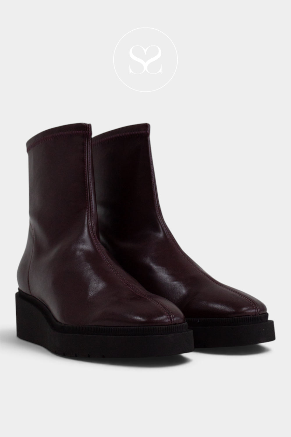 A pair of dark burgundy leather ankle boots with chunky black platform soles, shown against a light gray background with a faint circular Sheneil Shoes logo watermark at the top.
