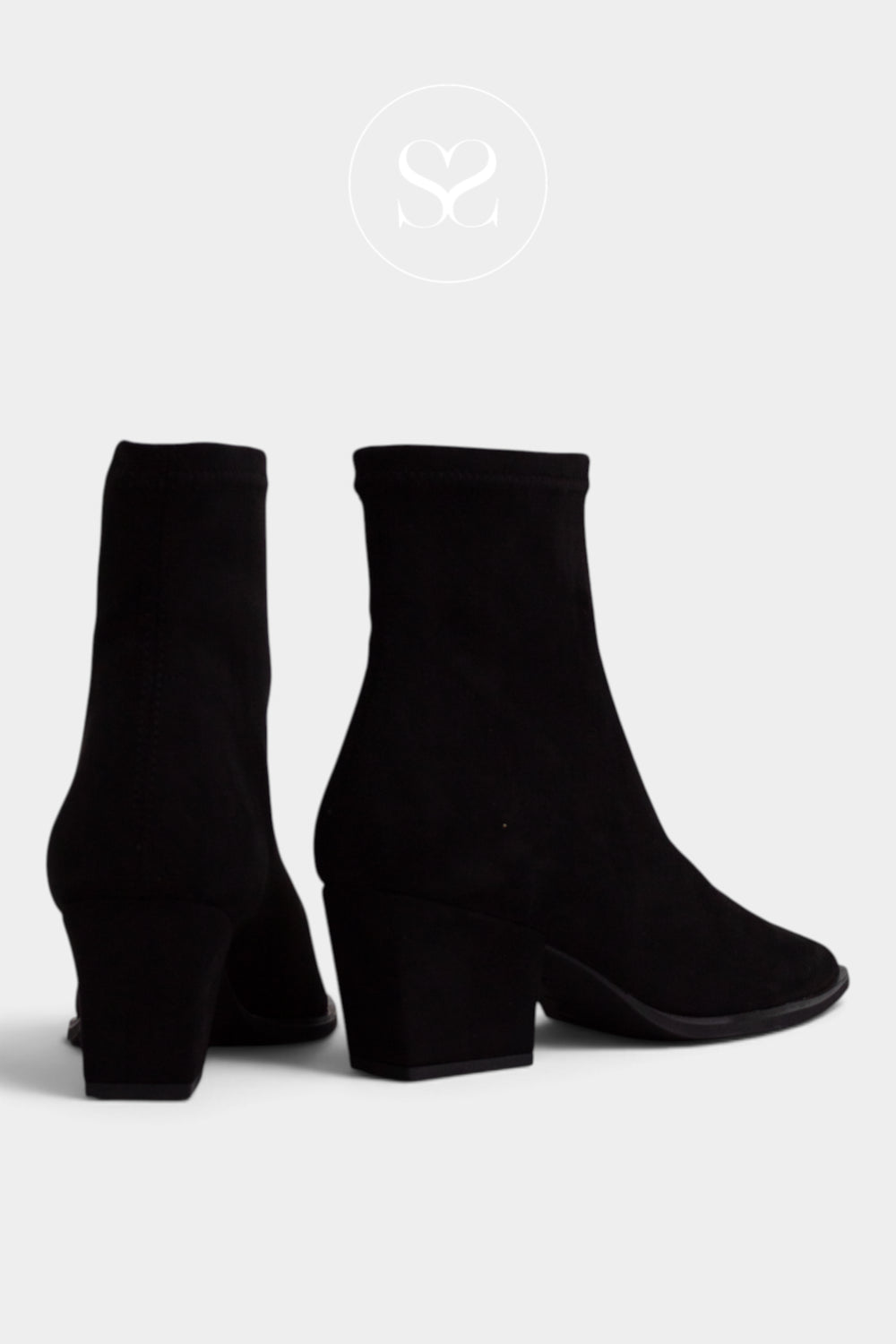 A pair of black suede ankle boots with block heels, shown from a three-quarters angle on a light gray background with a faint circular logo at the top.