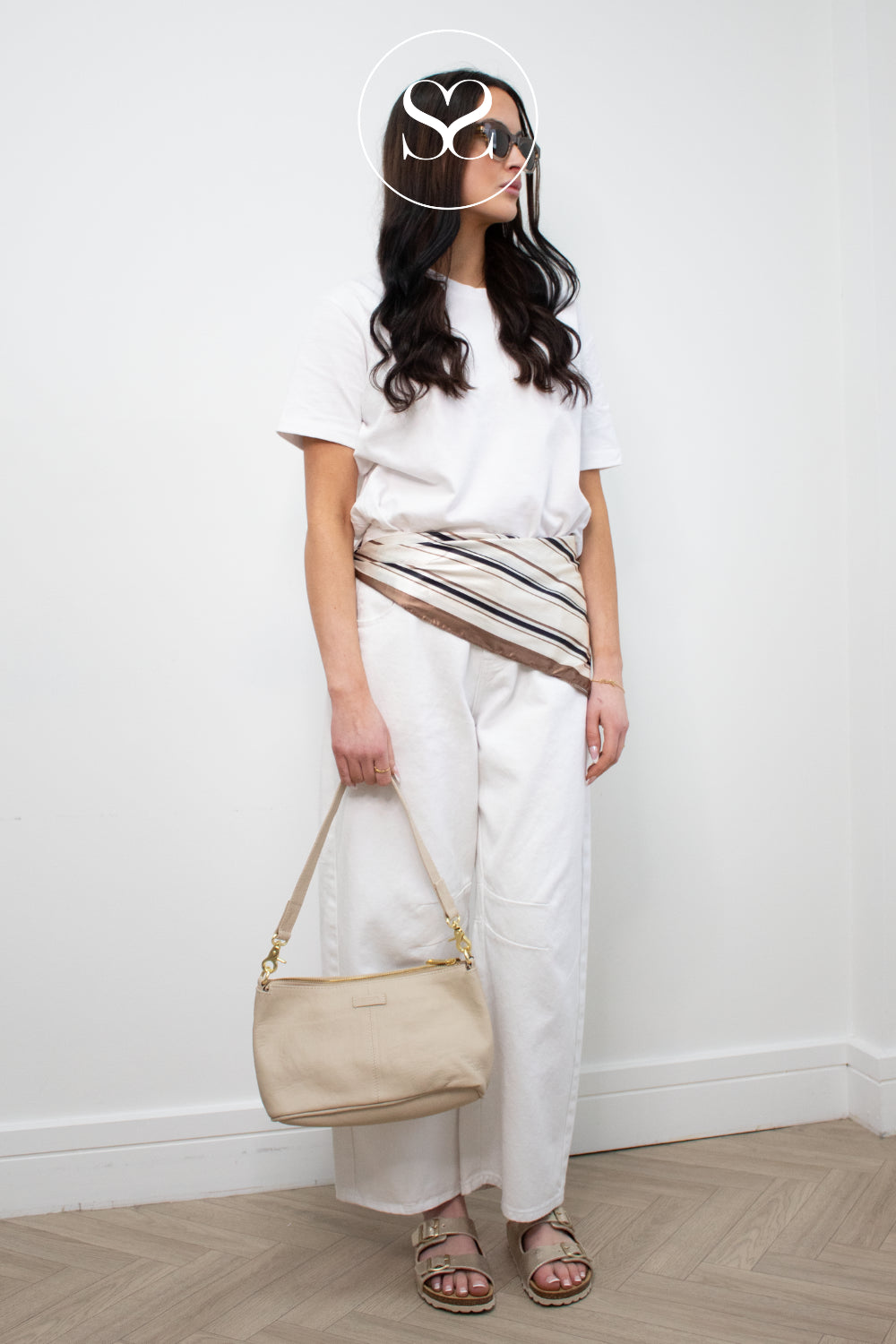 Model wearing gold toni pons slider sandals styled with a white outfit and sand coloured depeche leather handbag for everyday