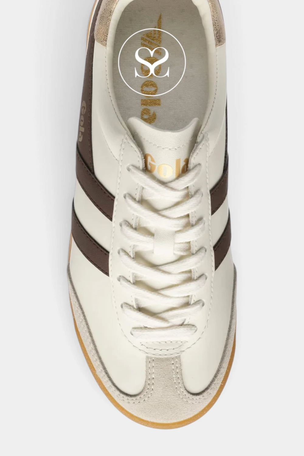A top-down view of a low-top sneaker in off-white leather and suede with dark brown side stripes, a white laces, and a light brown gum sole. The brand logo 'S.